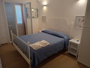 Ein Schlafzimmer mit einem Einzelbett, einem Nachttisch und einem an der Wand befestigten Regal.
