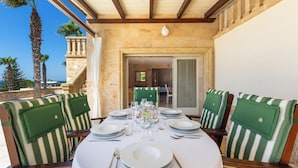 Un coin repas avec une table dressée pour six personnes, entourée de chaises à rayures, sous un plafond en bois.