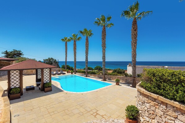 A pool area with a clear view of the sea, surrounded by palm trees and a gazebo. - Dimora Mina by BarbarHouse (Patù)
