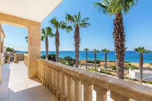 A balcony with a stone balustrade overlooking a coastal view with palm trees and the sea. - Dimora Mina by BarbarHouse (Patù)
