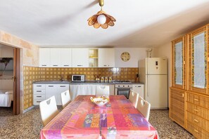 A compact kitchen with a dining table, chairs, a microwave, a stove, and a refrigerator. - Dimora Mina by BarbarHouse (Patù)