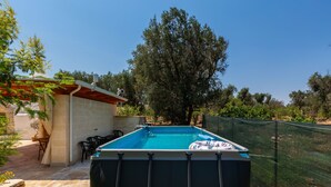 A swimming pool with a safety fence, a patio area with chairs, and a stone wall. - Trullo Sobba Llera by BarbarHouse (San Michele Salentino)