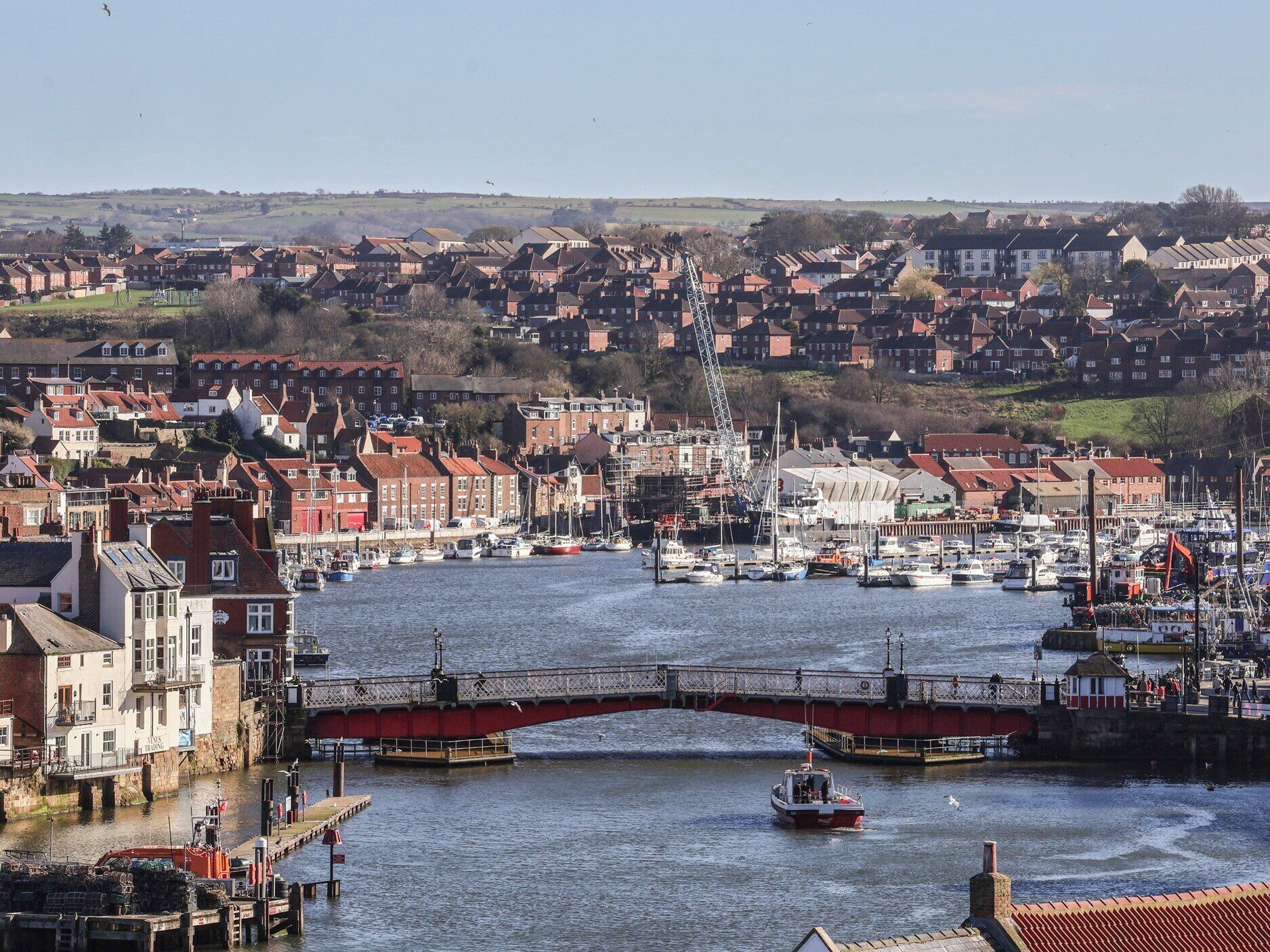 A harbor with boats, a bridge, and residential buildings in the background.