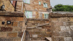 Escadaria de pedra que leva a um edifício com várias janelas e guarda-corrimão de metal.