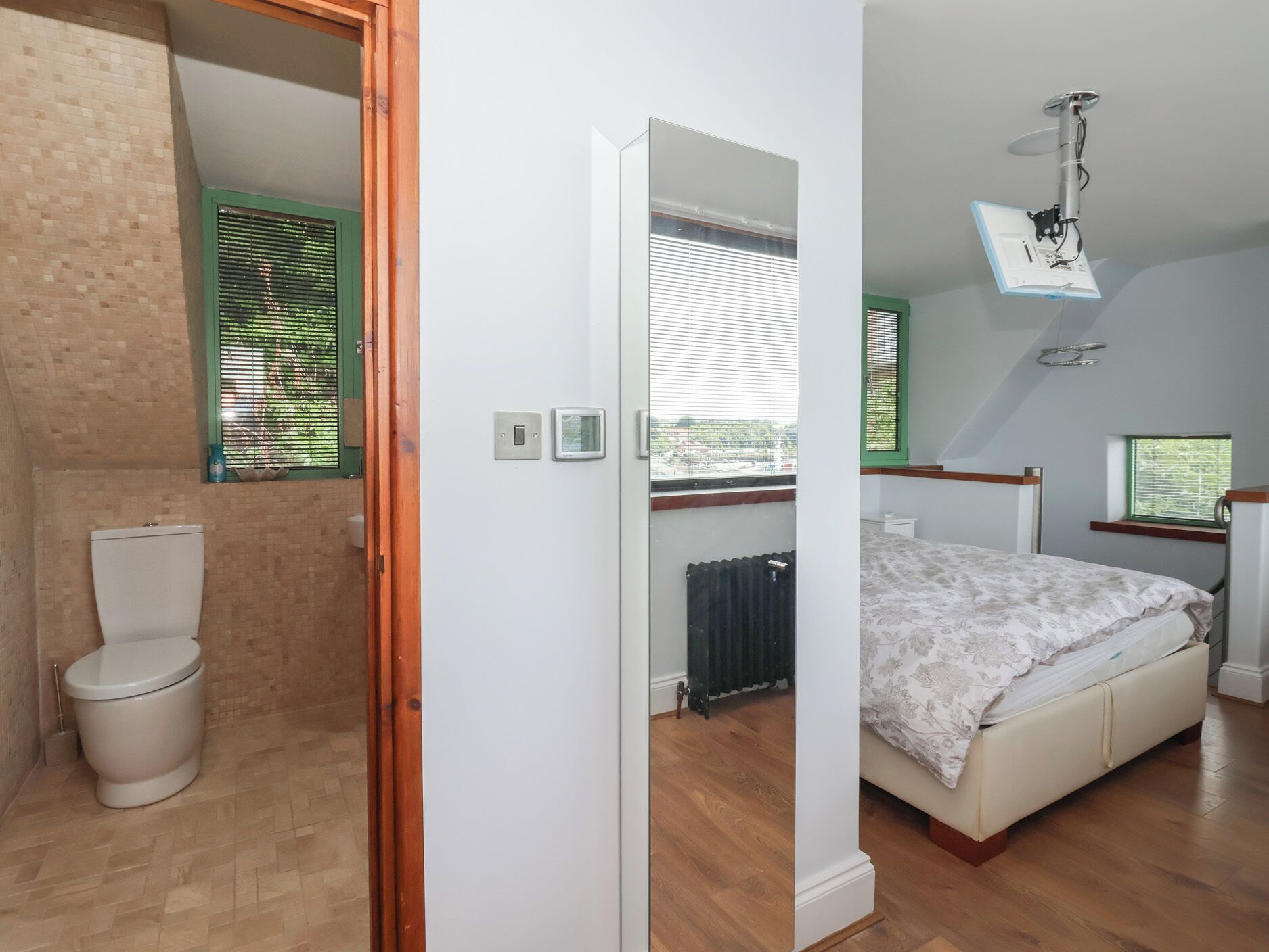 A bedroom with a bed, a window, a radiator, and a toilet.