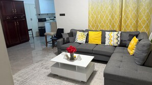 A modern living room with a grey sofa, a white coffee table, and a red vase. - Savannah Sunset- Charming 2 Bedroom Home with AC and Community Pool (Runaway Bay)