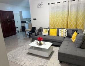 A modern living room with a grey sofa, a white coffee table, and a red vase. - Savannah Sunset- Charming 2 Bedroom Home with AC and Community Pool (Runaway Bay)