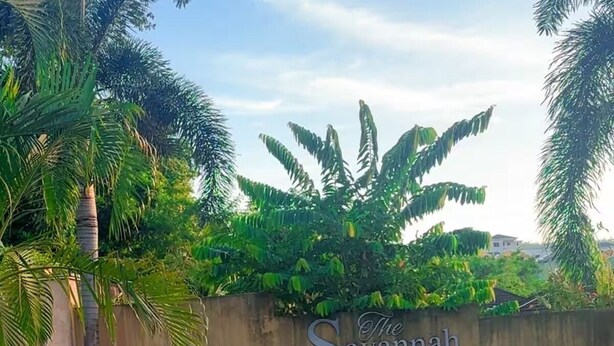 A sign for 'The Savannah at The Vistas' with a concrete wall and greenery in the background. - Savannah Sunset- Charming 2 Bedroom Home with AC and Community Pool (Runaway Bay)