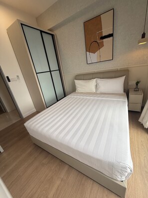 Een hotelkamer met een groot bed, een nachtkastje, een kunstwerk aan de muur en een schuifdeurkast.