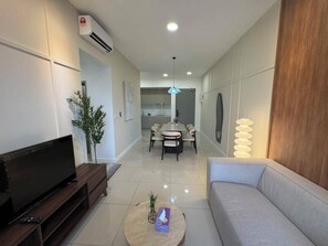 A modern living room with a flat-screen TV, a sofa, a dining table with chairs, and a kitchen in the background. - Skyline Dream stay Luxury suite KL (Kuala Lumpur)