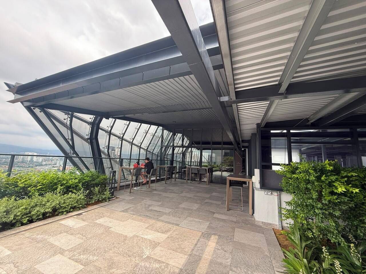 Una terraza moderna en la azotea con techo de vidrio, mobiliario exterior y vistas de la ciudad.