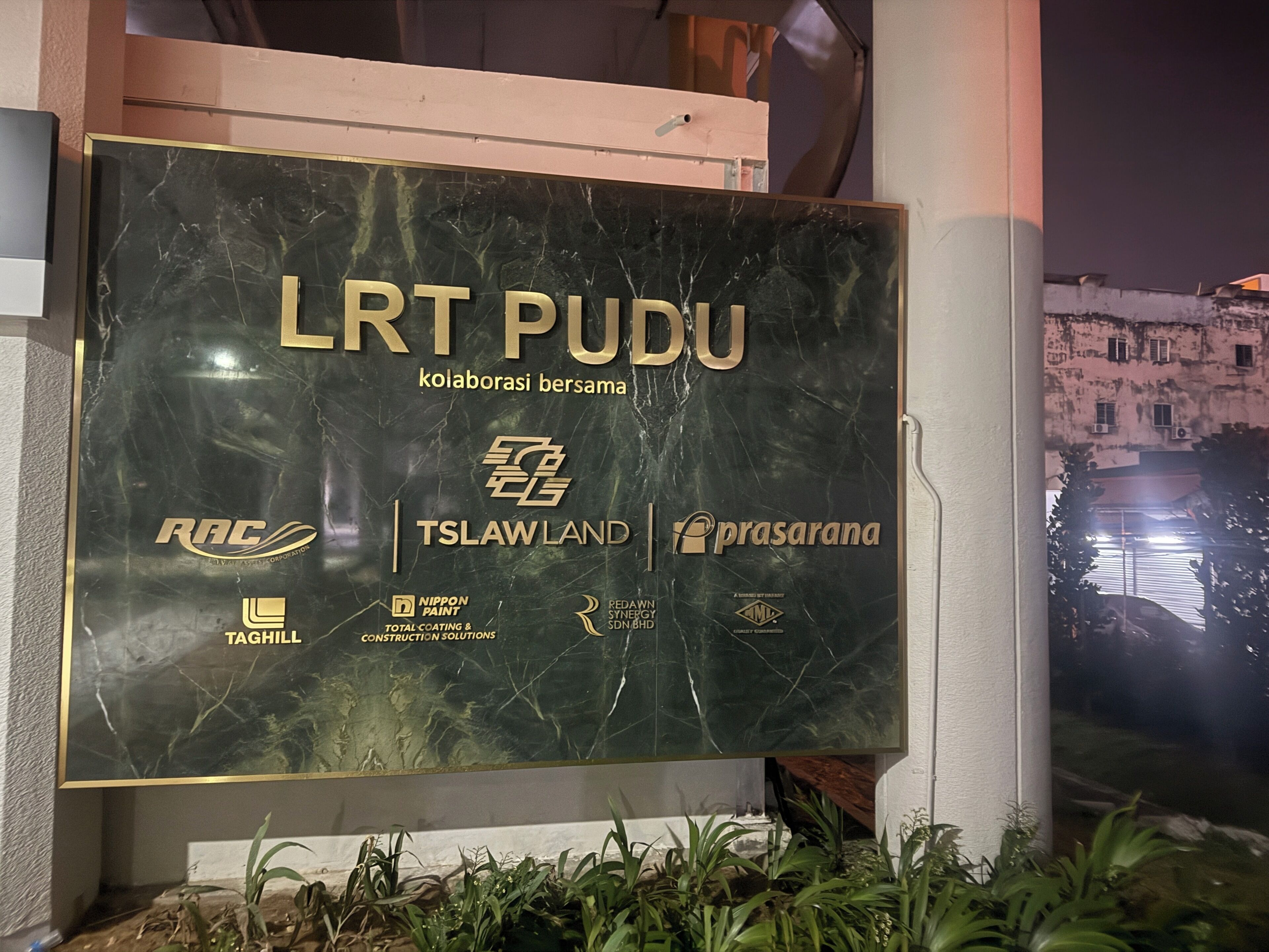 Un segnale con il testo 'LRT PUDU' e i loghi di diverse aziende.