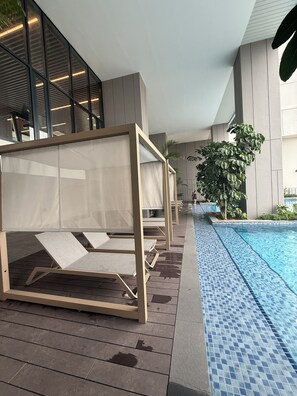 A poolside area with lounge chairs and a tiled pool. - Skyline Dream stay Luxury suite KL (Kuala Lumpur)