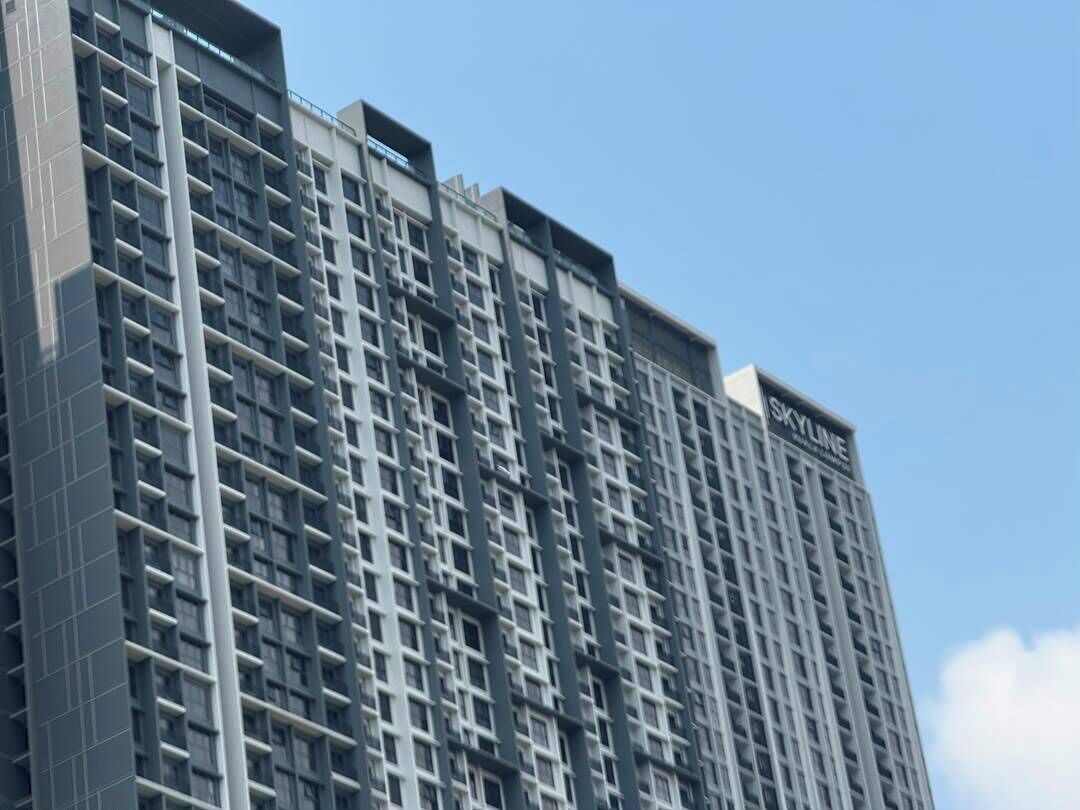A high-rise building with a grid-like facade, multiple balconies, and the name 'SKYLINE' visible on the top.