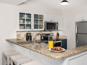 A modern kitchen with white cabinetry, a granite countertop, a stainless steel refrigerator, a microwave, and a sink with a faucet. - 3 Bedroom Villa Beach Access at SurfWatch Resort (Hilton Head Island)
