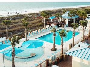 A pool area with lounge chairs and umbrellas, a beach view, and a building with a blue roof. - 3 Bedroom Villa Beach Access at SurfWatch Resort (Hilton Head Island)