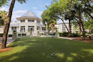 Un campo da golf con un gazebo, palme e un edificio dalla facciata bianca.