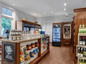 Ein Ladeninneres mit einer Feinkosttheke, gekühlten Kühlvitrinen und einer Auswahl an Snacks und Getränken.
