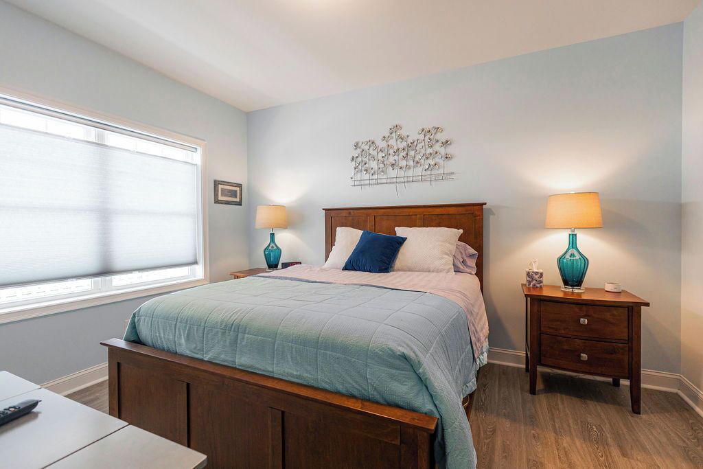 A bedroom with a bed, bedside tables, a lamp, a wall decoration, and a window.