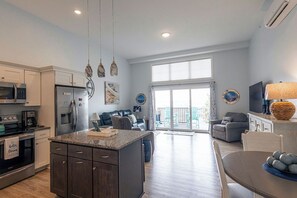 A modern kitchen with granite countertops, stainless steel appliances, and a central island. - Breezy Beach Haven - 3rd story 1 bedroom condo w ac, laundry, deck, elevator. (Hampton)