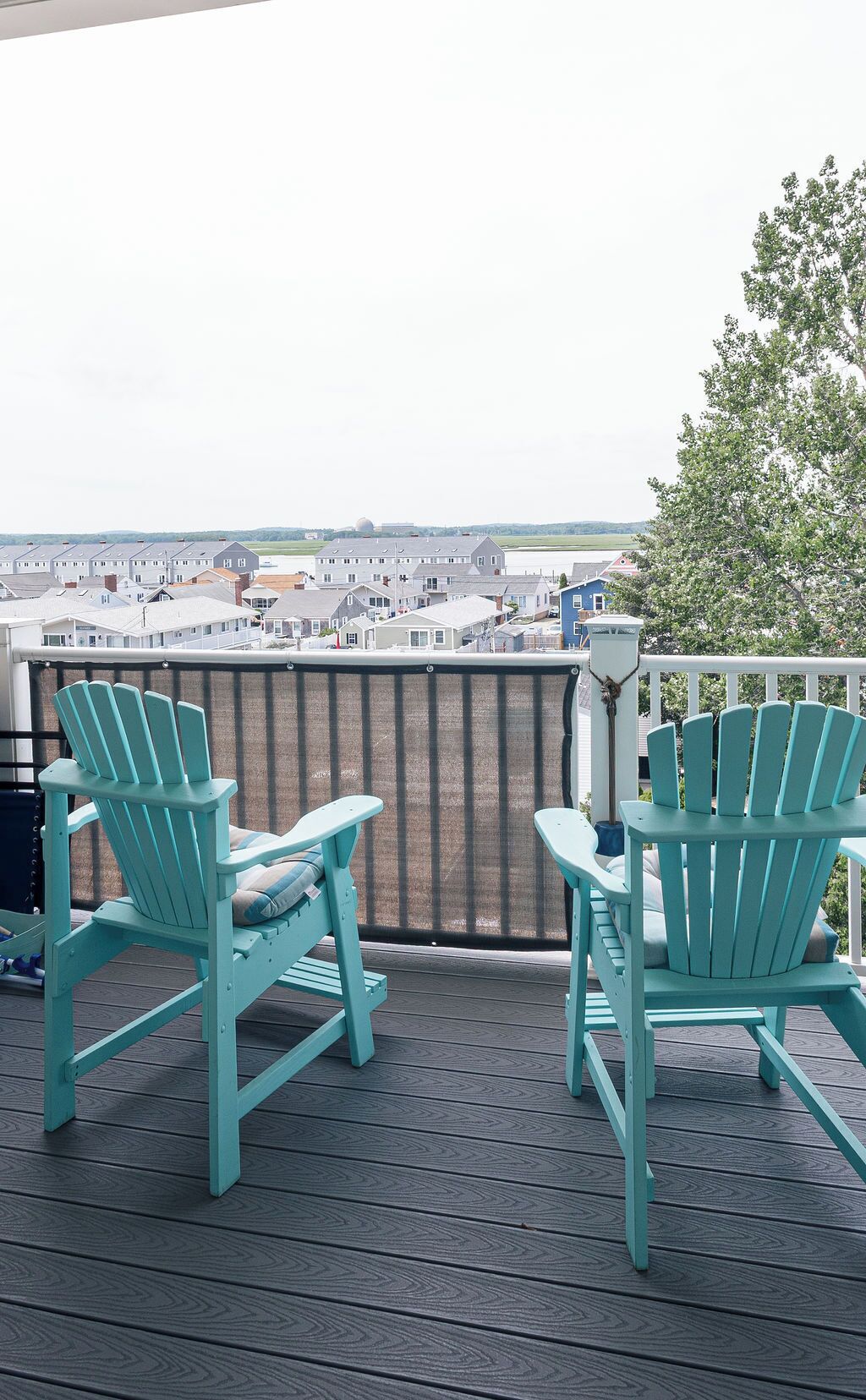 Een terras met twee stoelen en een tafel, met uitzicht op een woonwijk.