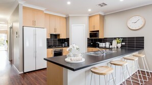 Una cocina moderna con una isla central, taburetes de bar y un reloj en la pared.