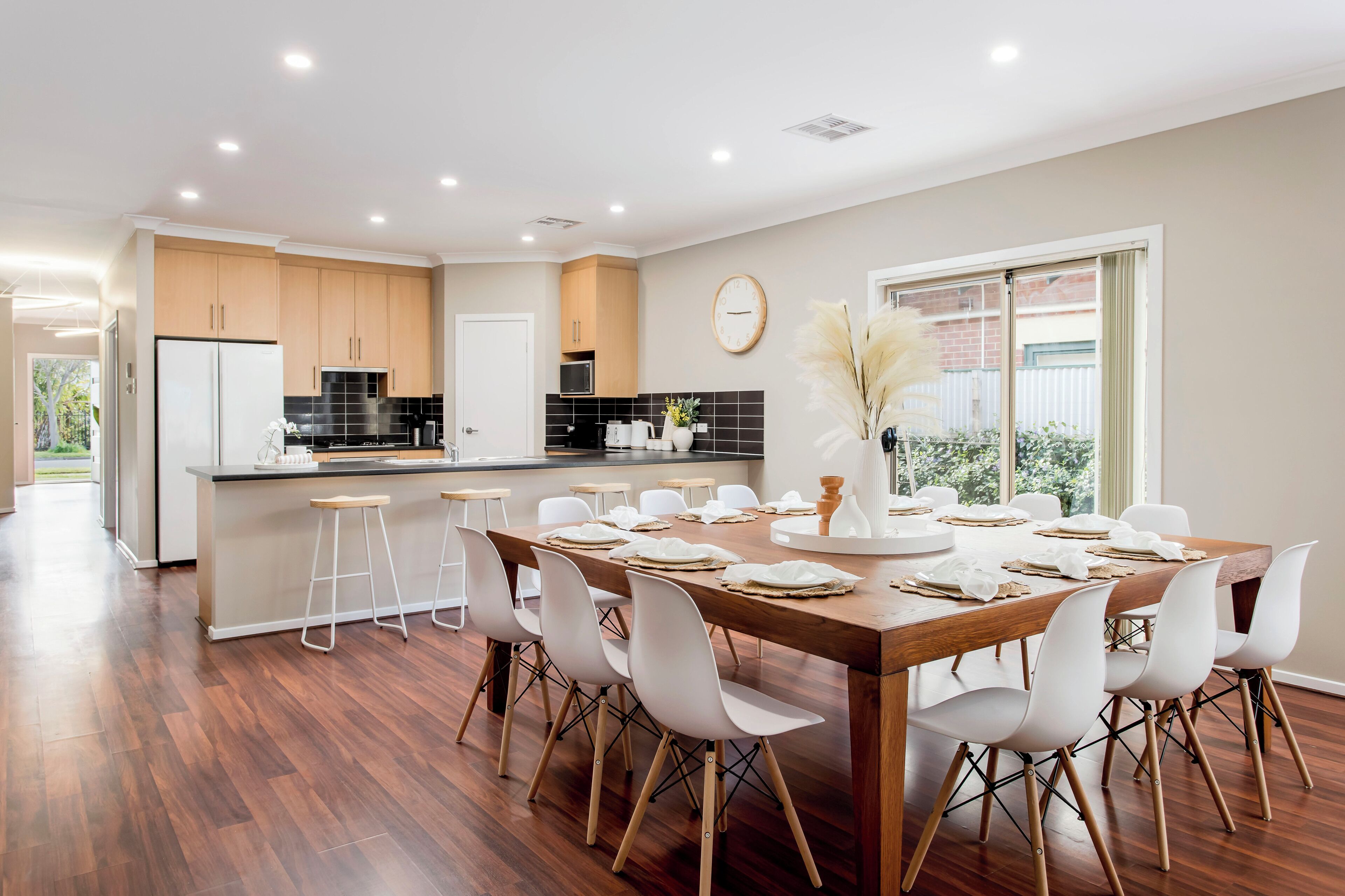 A modern kitchen with wooden cabinets, a central island, and a dining area with a wooden table set for six.