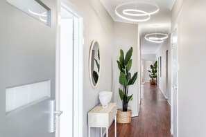 A modern hallway with a wooden floor, white walls, and a ceiling with circular light fixtures. - Lumina A Spacious Haven Close to Adelaides Best (Allenby Gardens)