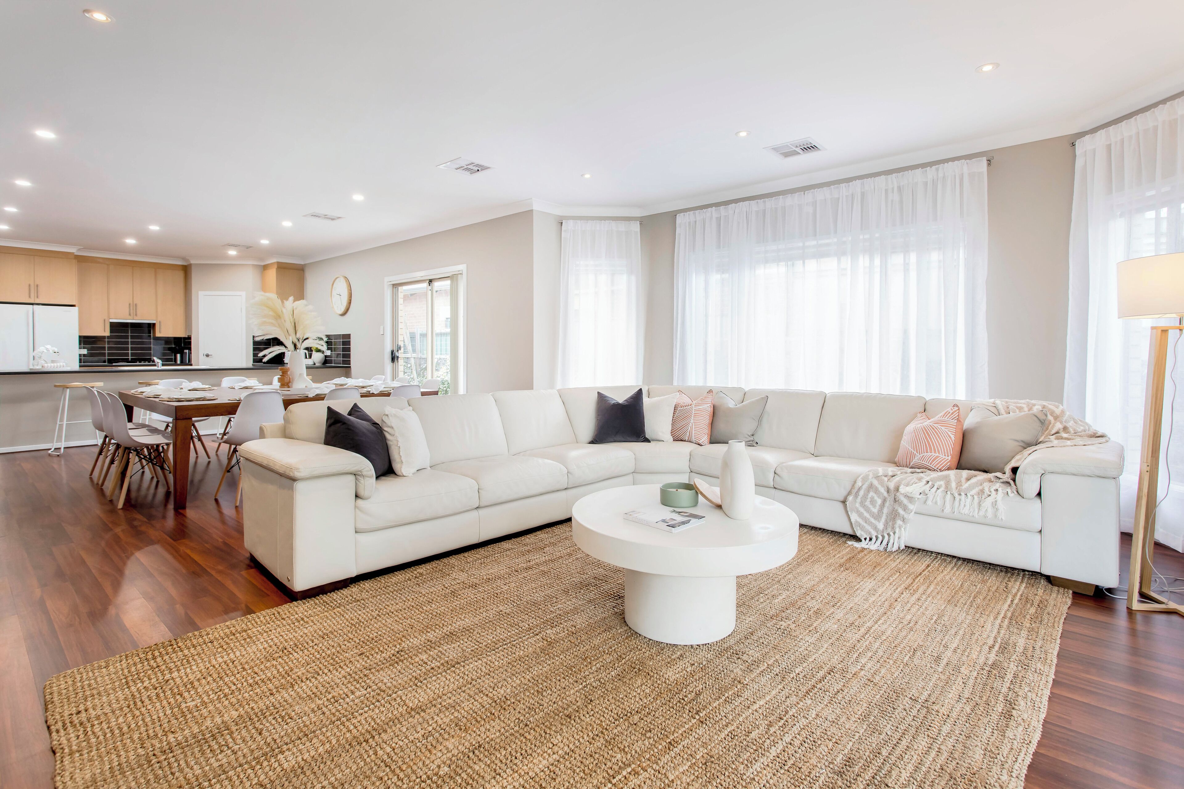 A modern living room with a sectional sofa, a coffee table, and a dining area with chairs.