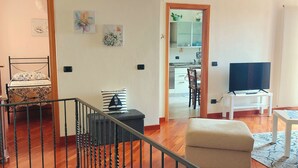 Un soggiorno con un letto, una TV, un tavolo da pranzo e una cucina sullo sfondo.