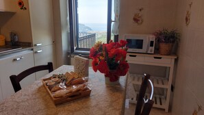 Una cucina con vista sul mare, un forno a microonde, un vaso con fiori e un vassoio per il pane.