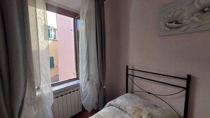 Una camera da letto con un letto, un termosifone, una finestra con tende e un'opera d'arte appesa al muro.