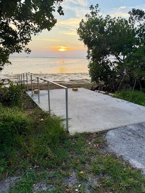 A concrete pathway leading to a body of water with a sunset in the background. - Renovated Coastal Retreat- Walk to water, includes bikes, Bike to Pinellas Trail (Palm Harbor)