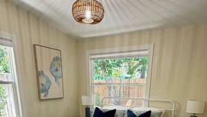 Un dormitorio con cama, dos mesitas de noche, una ventana y una lámpara en el techo.