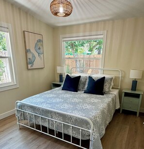 A bedroom with a bed, two bedside tables, a window, and a ceiling light fixture. - Renovated Coastal Retreat- Walk to water, includes bikes, Bike to Pinellas Trail (Palm Harbor)