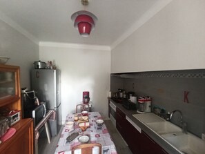 Una cocina estrecha con un refrigerador, una cafetera y un lavamanos.