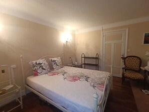 A bedroom with a bed, a chair, a shelf, and a door. - 2-Bedroom Country House in the Heart of Quercy-Périgord (Gourdon)