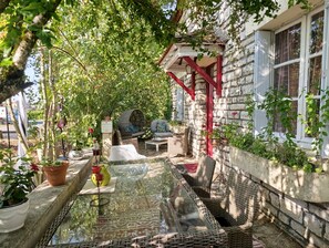 A sunlit outdoor seating area with wicker furniture, a glass table, and potted plants. - 2-room Country House in the Heart of Quercy-Périgord (Gourdon)