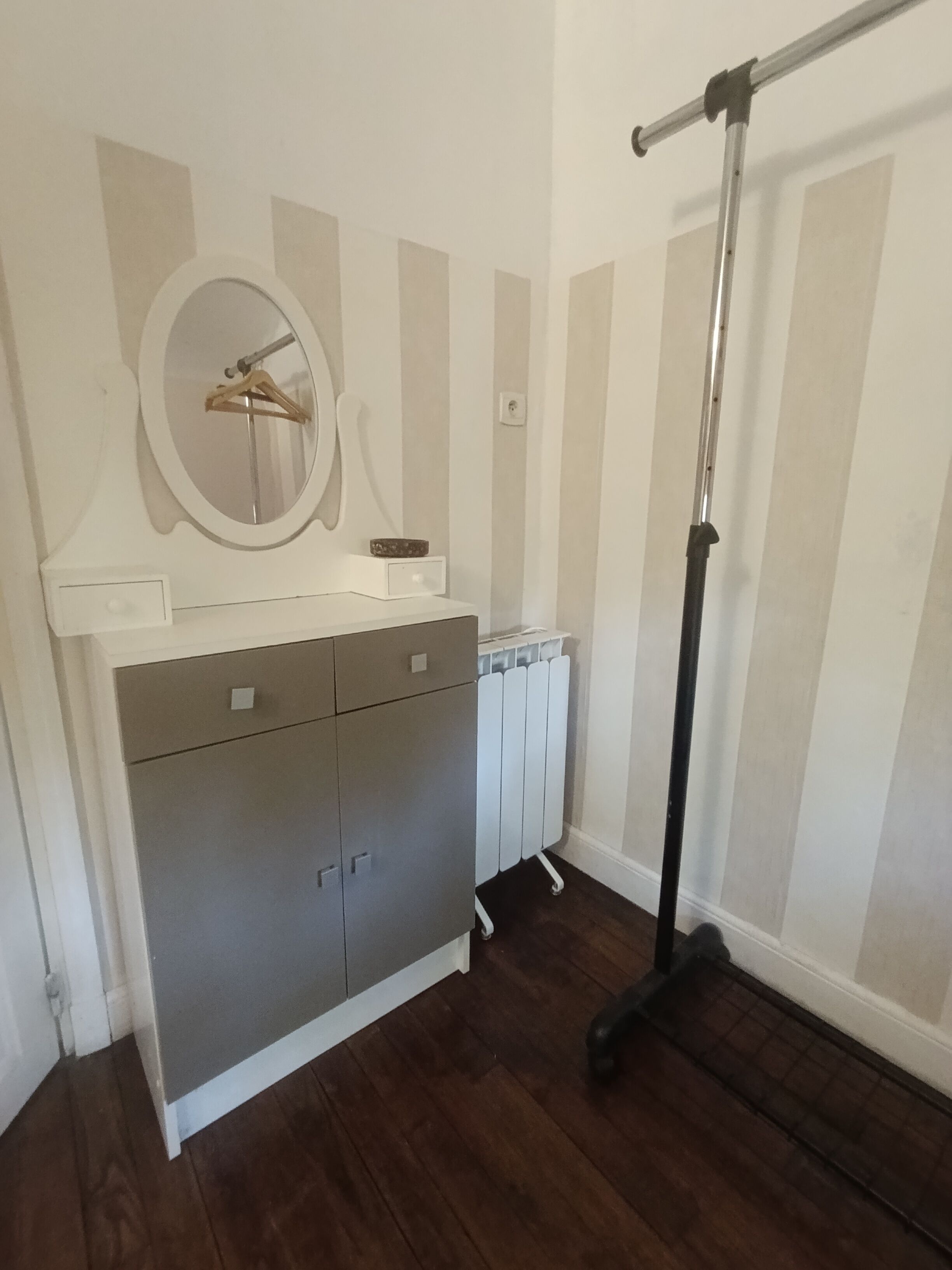 Une pièce avec un meuble gris, un radiateur blanc et un lampadaire noir.