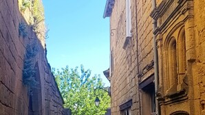 En smal gränd med kullerstenar, innesluten av hus med valvformade dörröppningar, och ovanför syns en klarblå himmel.