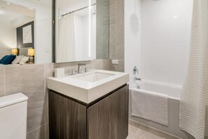 Un baño moderno con lavamanos, espejo y bañera.