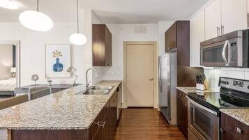 Una cocina moderna con encimeras de granito, electrodomésticos de acero inoxidable y suelo de madera.