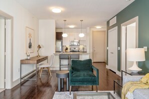 Una sala de estar moderna con comedor, cocina y una pared verde decorativa.