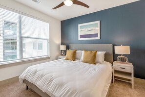 A bedroom with a bed, two bedside tables, a ceiling fan, a window with blinds, and a framed picture on the wall. - Landing Beautiful 1bd, Courtyard, Clubhouse (Goodyear)