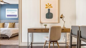 A bedroom with a bed, a desk with a chair, a framed picture, and a small plant. - Landing Amazing 1BD in Bear Creek (Houston)
