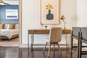 A bedroom with a bed, a desk with a chair, a framed picture, and a small plant. - Landing Amazing 1BD in Bear Creek (Houston)