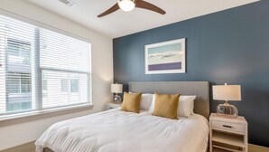 A bedroom with a bed, two bedside tables, a ceiling fan, a window with blinds, and a framed picture on the wall. - Landing Amazing 1BD in Bear Creek (Houston)