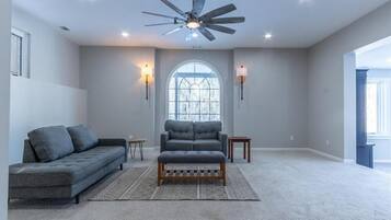 A spacious living room with a ceiling fan, two sofas, a coffee table, and a large window with a view.