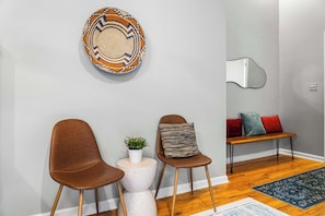 A room with two brown chairs, a round table with a plant, a bench with cushions, and a decorative wall piece. - 6BR, Sleeps 16, Game Room, Hot Tub, Resort Access (Albrightsville)