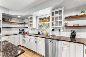 A modern kitchen with white cabinetry, a granite countertop, and a window with a view of a garden. - 6BR, Sleeps 16, Game Room, Hot Tub, Resort Access (Albrightsville)